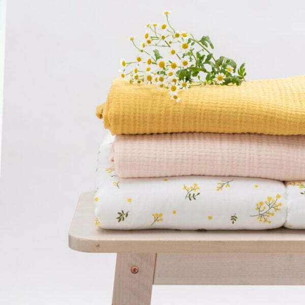 three folded muslin cloths, one in floral design, the second all in yellow and the third grey
