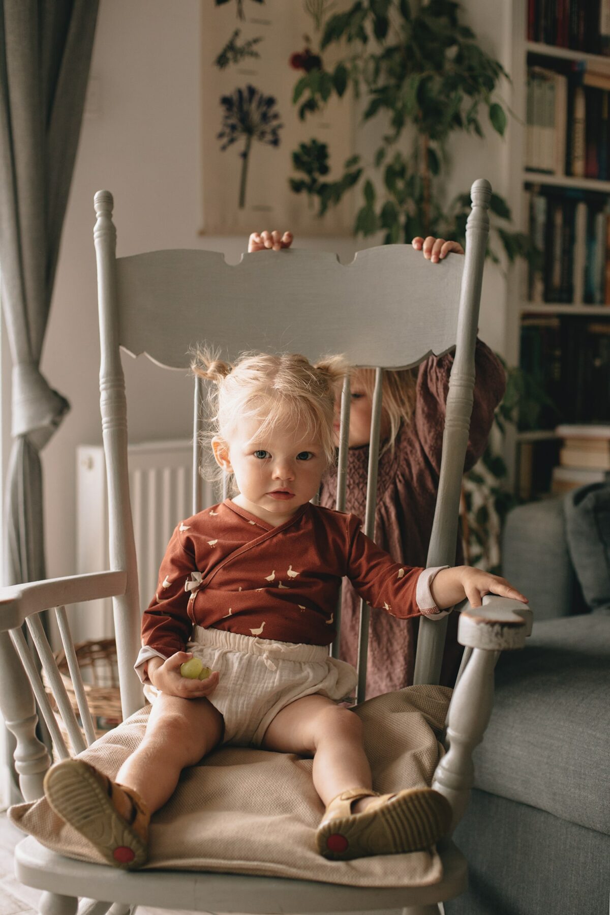 Ein Mädchen im Zimmer gekleidet in Baby Wickelbody aus Bio-Baumwolle mit GOTs Zertifikat und langen Ärmel mit Gänse Muster