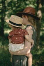 Ein Mädchen mit Mutter im Garten gekleidet in Baby Wickelbody aus Bio-Baumwolle mit GOTs Zertifikat und kurzen Ärmel mit Gänse Muster