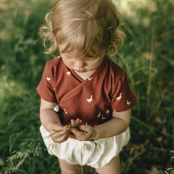 A girl dressed with Wrapover bodysuit with short sleeves – red brown little geese