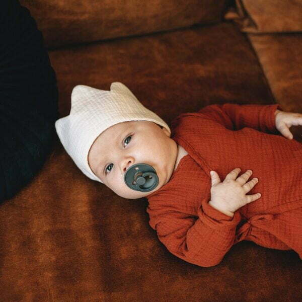 A baby gekleidet in einem Overall aus Musselin Bio Baumwolle in rotbrauner Farbe