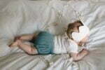 Ein Baby gekleidet in Baby Bloomers / Pumphose und Wickelhemd aus zertifiziertem Bio Musselin