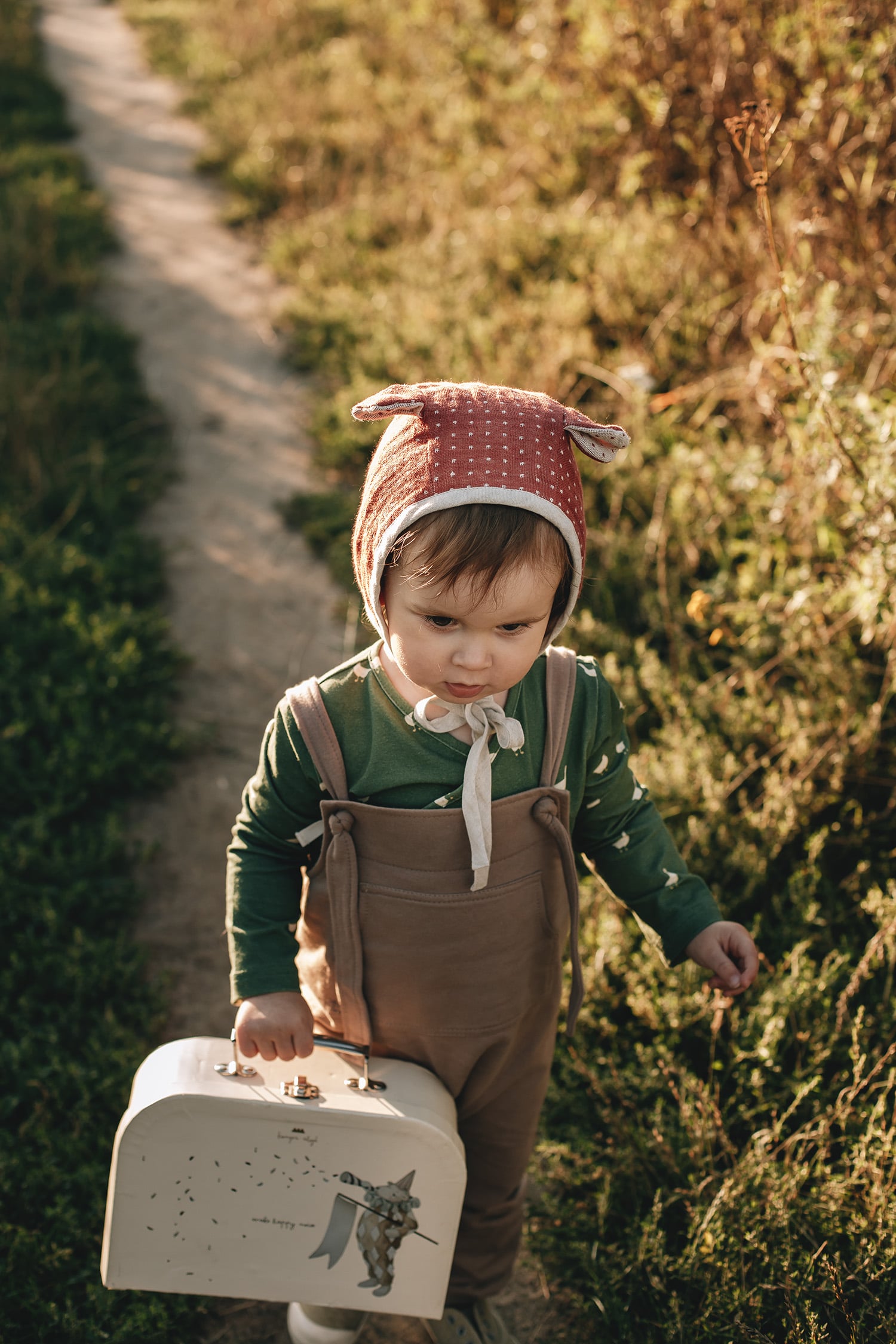 ein Junge auf der Weide gekleidet in einem Wickelbody mit Gänse Muster aus Bio Baumwolle